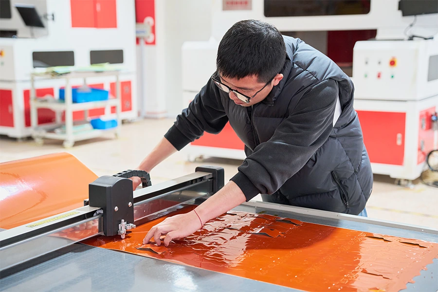 Worker preparing copper sheet at a worktable