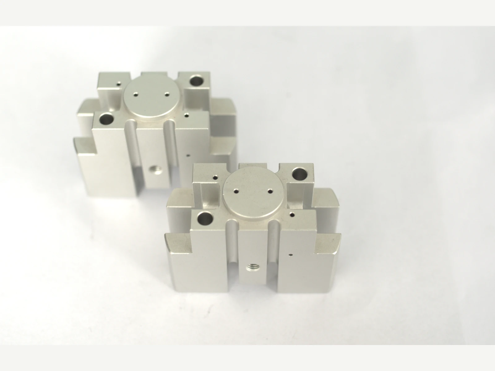 Machined metal sample components photographed on a light surface